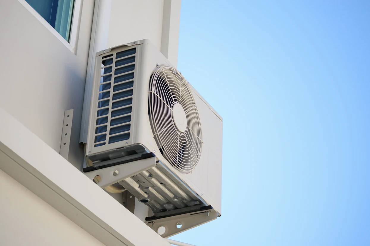 Extérieur d'un bâtiment blanc avec unité de climatisation montée sur façade sous ciel bleu clair