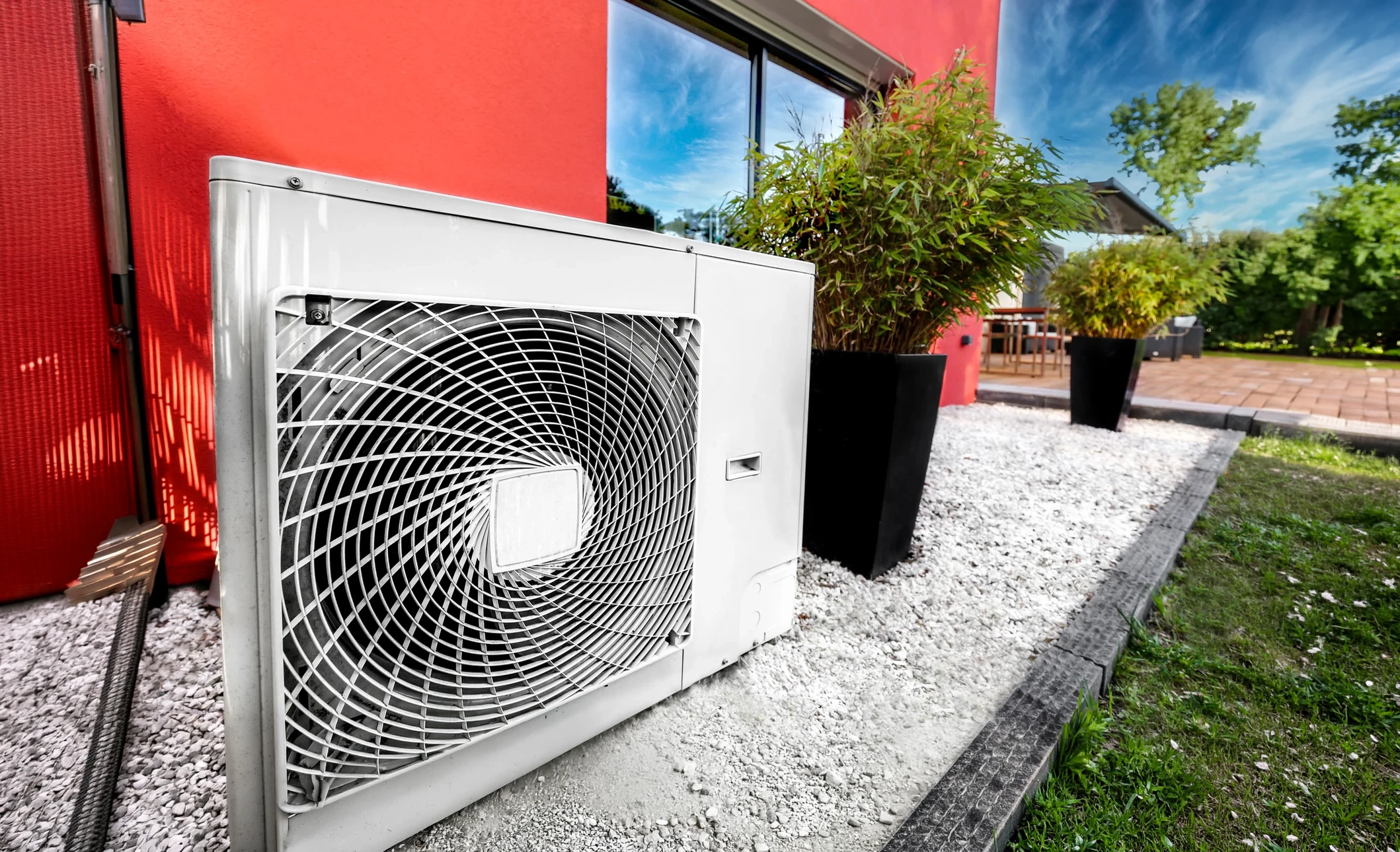 Unité extérieure de climatisation ou pompe à chaleur blanche montée sur mur en briques rouges